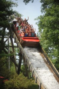 People on a log flume with their hands in the air.