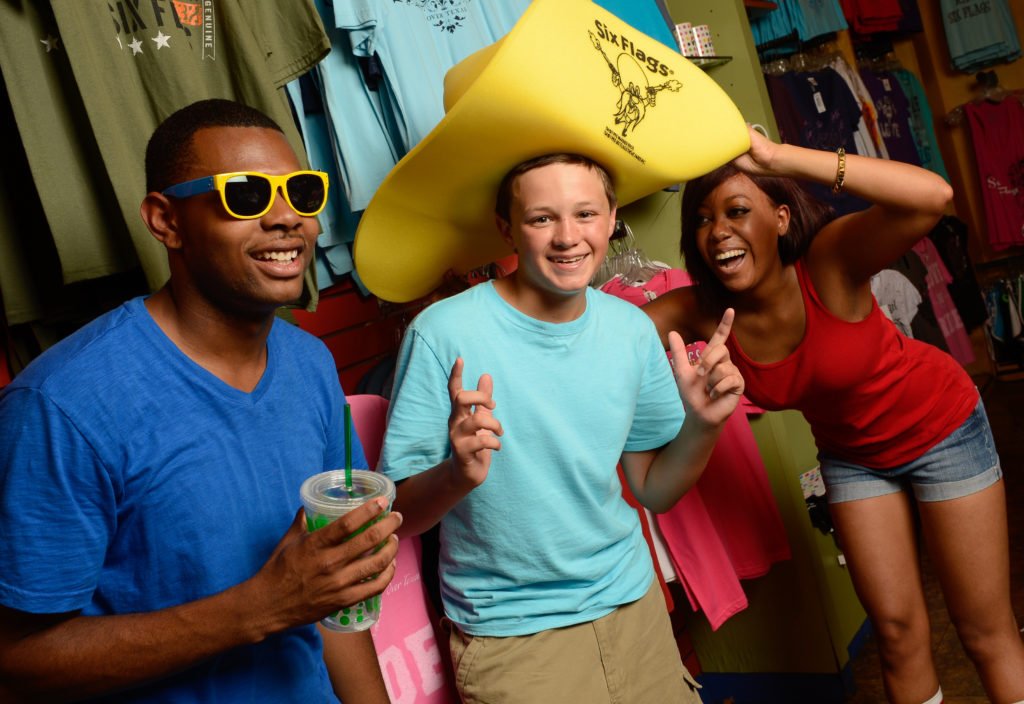 Three people smiling at the camera while shopping at a Six Flags theme park