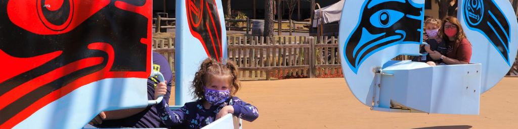 Children at Frontier City riding an attraction with masks