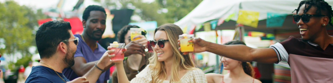 Group of six friends raising a toast with colorful beverages at the Six Flags Over Georgia Brews & Bites Festival