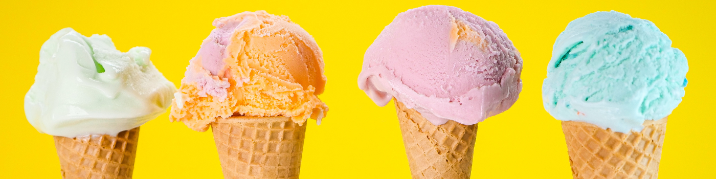 Multicolored ice cream on ice cream cones in front of a yellow background