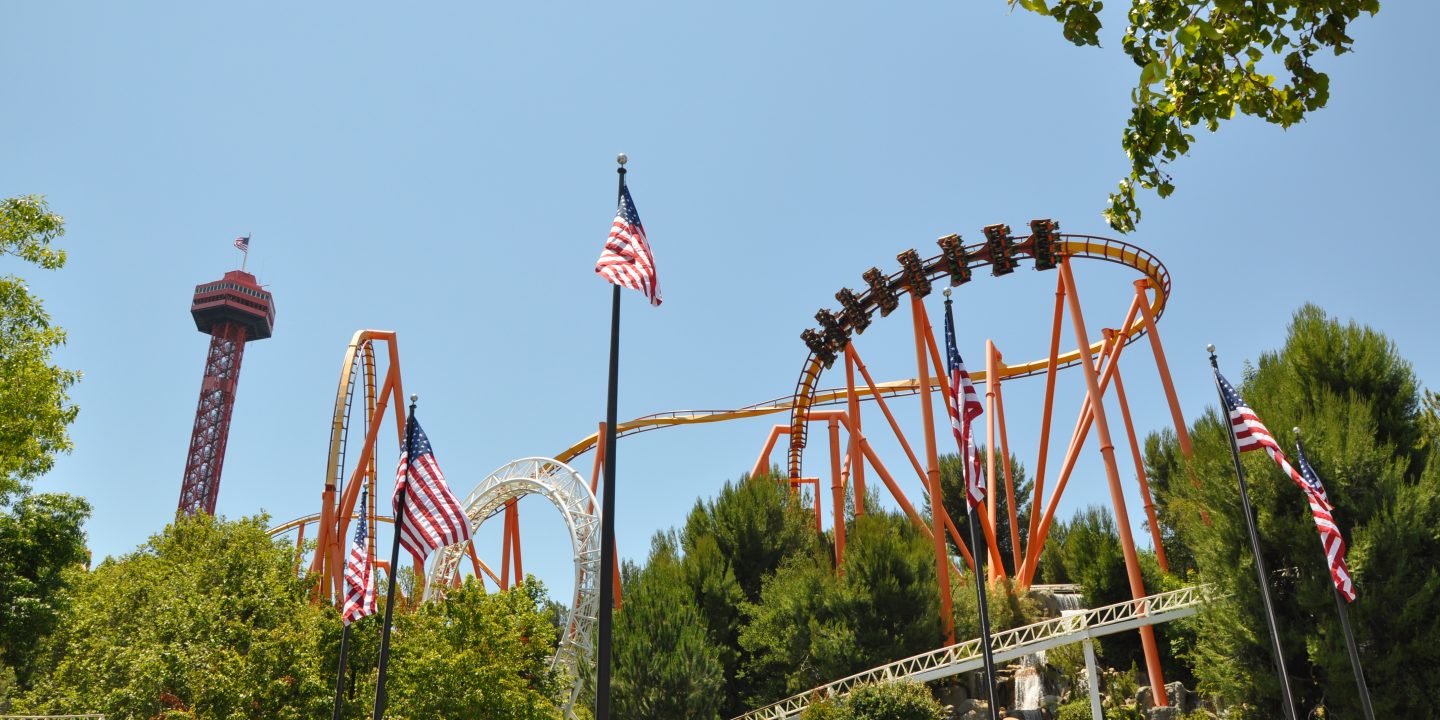 Six American flags flying at the park with a view of coasters at Six Flags