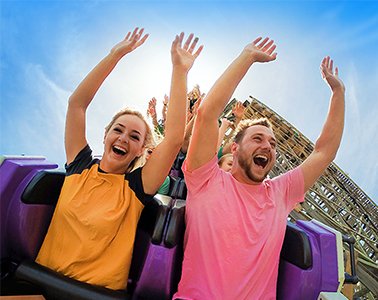 Women and Man Riding a Wooden Roller Coaster with Arms in Arm